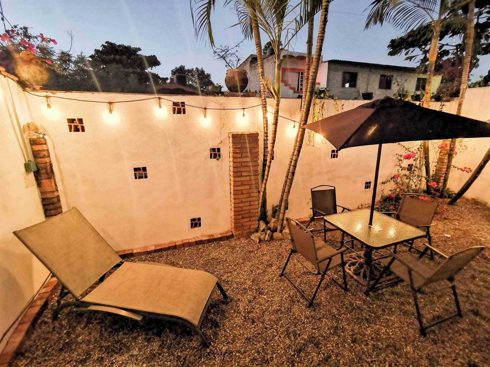 Hotel de Asis: private patio with string lights, a table and loungers at dusk