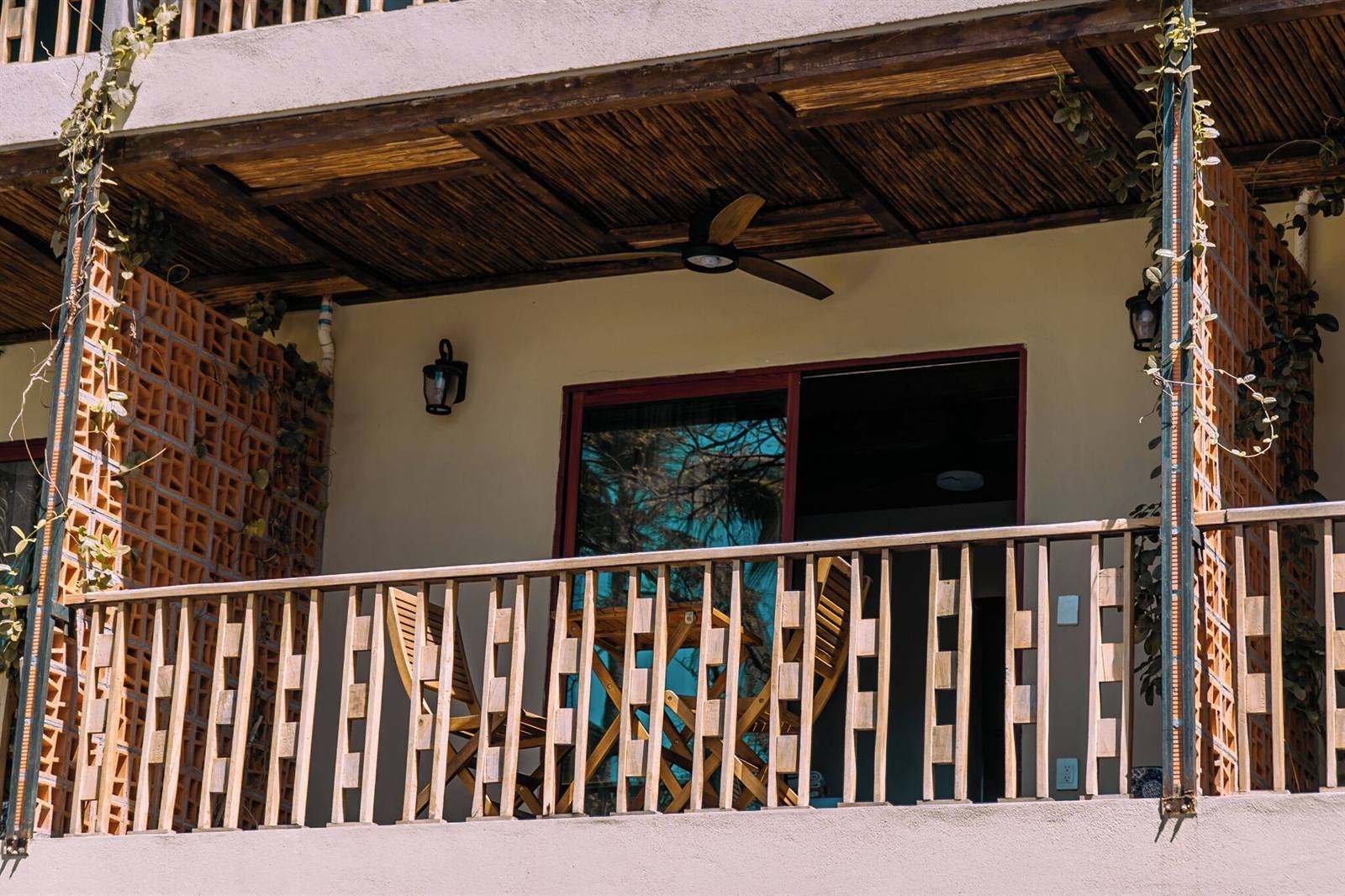 Hotel de Asis: covered balcony with a wooden railing and a ceiling fan